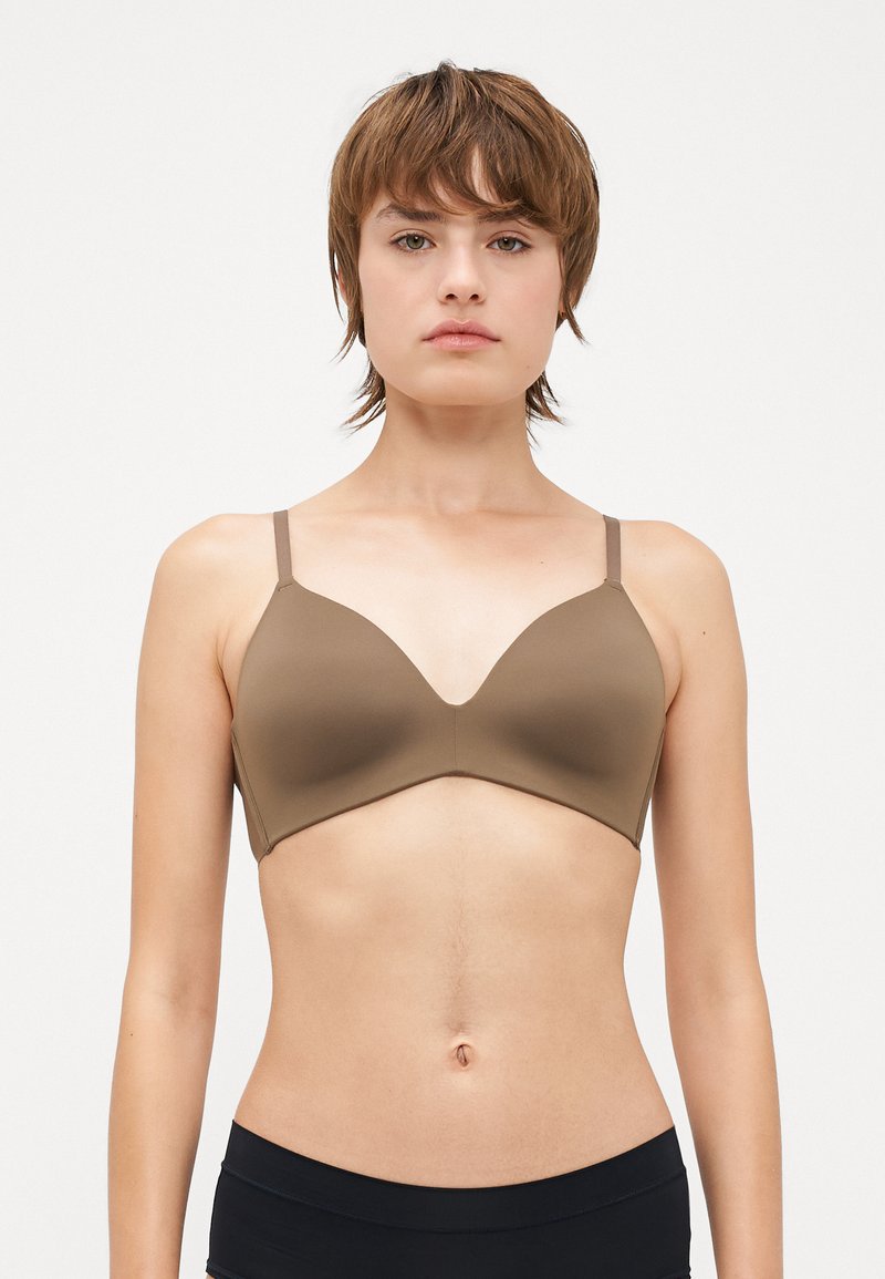 Brown seamless bra with a V-neck design, adjustable straps, and smooth texture, offering minimalistic coverage and support.