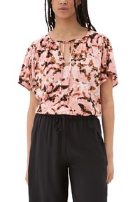 Leichtgewichtige rosa Bluse mit einem abstrakten Muster in Schwarz und Braun, Rundhalsausschnitt mit einer Schlitzöffnung und kurzen, flatternden Ärmeln. Kombiniert mit schwarzen Hosen.
