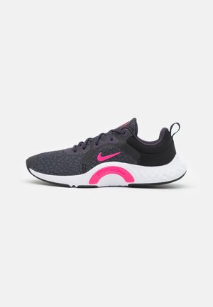 Ciemnoszary but sportowy z różowym logo Nike i dodatkami, biała podeszwa oraz pętelka na pięcie, widok z boku na białym tle.