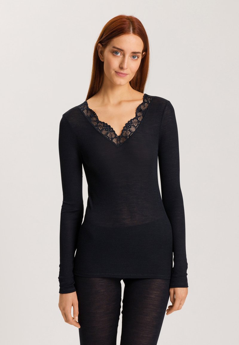 Top nero a maniche lunghe con scollatura a V e bordo in pizzo. Il tessuto presenta una texture a coste, offrendo una silhouette aderente.