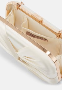 Kremowa kopertówka z satyny z metalową ramką w złotym odcieniu. Posiada marszczoną teksturę oraz wewnętrzną metkę. Zapięcie jest bezpieczne.