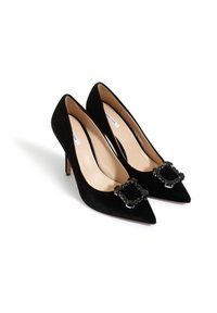 Czarne zamszowe szpilki z ostrymi noskami, wyposażone w ozdobne klamry na cholewce i smukłe obcasy. Gładkie wykończenie wewnętrzne.