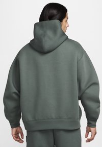 Sweatshirt com capuz oversized em verde suave, feito de material macio. Apresenta um capuz arredondado e punhos e bainha canelados para um ajuste descontraído.