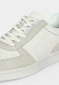 Baskets en daim blanc et gris clair avec fermeture à lacets et marquage embossé "Marc O'Polo" sur le côté.