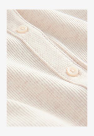 Tissu côtelé beige clair avec trois boutons le long de la patte de boutonnage, offrant une texture douce et une légère variation de couleur sur l'ensemble.