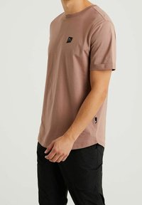 Tričko s krátkým rukávem a kulatým výstřihem v barvě prachové růže vyrobené z bavlněné tkaniny. Obsahuje malou černou nášivku s logem na hrudi a rovný lem.