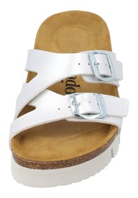 Vita lädersandaler med två justerbara silverspännen, en korkfotbädd och en strukturerad tanfärgad innersula. Sålen är vit och något upphöjd.