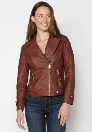 Red leather biker jacket with a wide collar, asymmetrical zipper, two zippered pockets, and button accents on cuffs. Textured finish.