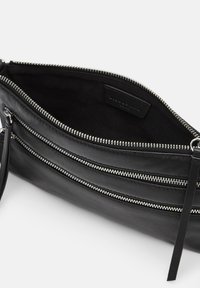 Borsa in pelle nera con cerniere d'argento, dotata di tre scomparti con cerniera e una texture liscia. All'interno è foderata di nero.