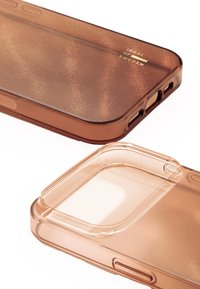 Transparante bruine telefoonhoes met een glinsterende afwerking, voorzien van gladde randen, nauwkeurige uitsparingen voor knoppen en een slank ontwerp.