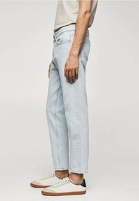 Světle modré džíny s uvolněným střihem a rovnými nohavicemi. Nosené s bílými teniskami se béžovými a tmavě modrými akcenty.