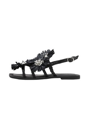 Sandalia plana negra con tiras trenzadas, detalles florales decorativos en blanco y negro y hebilla ajustable en el tobillo.
