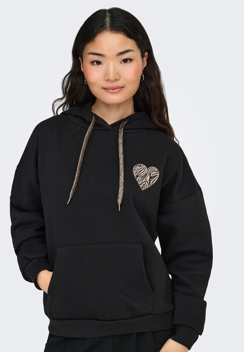 Sudadera negra con capucha que presenta un aplique en forma de corazón con patrón de cebra en el lado izquierdo del pecho, con cordones metálicos dorados y un bolsillo frontal.