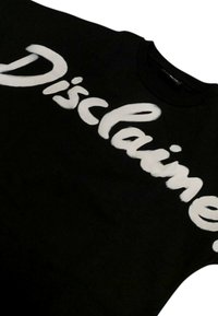 T-shirt in cotone nero con grande testo bianco che recita "Disclaim." Tessuto liscio con colletto girocollo e maniche corte.