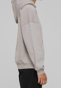 Sweat à capuche gris clair avec une coupe décontractée, doté d'une capuche à cordon, de poches latérales, de poignets et d'un ourlet côtelés, fabriqué dans un tissu doux.