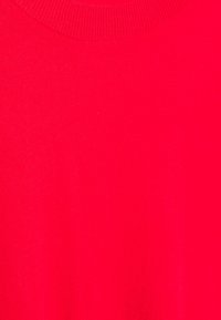 Roter Strickpullover mit Rundhalsausschnitt, glatter Textur und einheitlicher Farbausprägung im gesamten Stoff. Keine sichtbaren Muster oder Akzente.