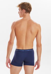 Marineblaue Boxershorts mit einem weichen Bund, der die Marke "JBS UNDERWEAR" trägt, aus einem glatten, dehnbaren Stoff gefertigt.