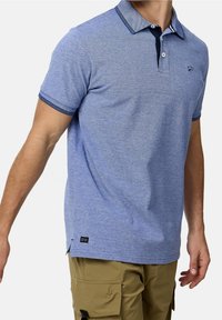 Polo shirt bleu en tissu texturé, avec un col et des poignets contrastés, un patte de boutonnage à trois boutons et un détail de logo discret.