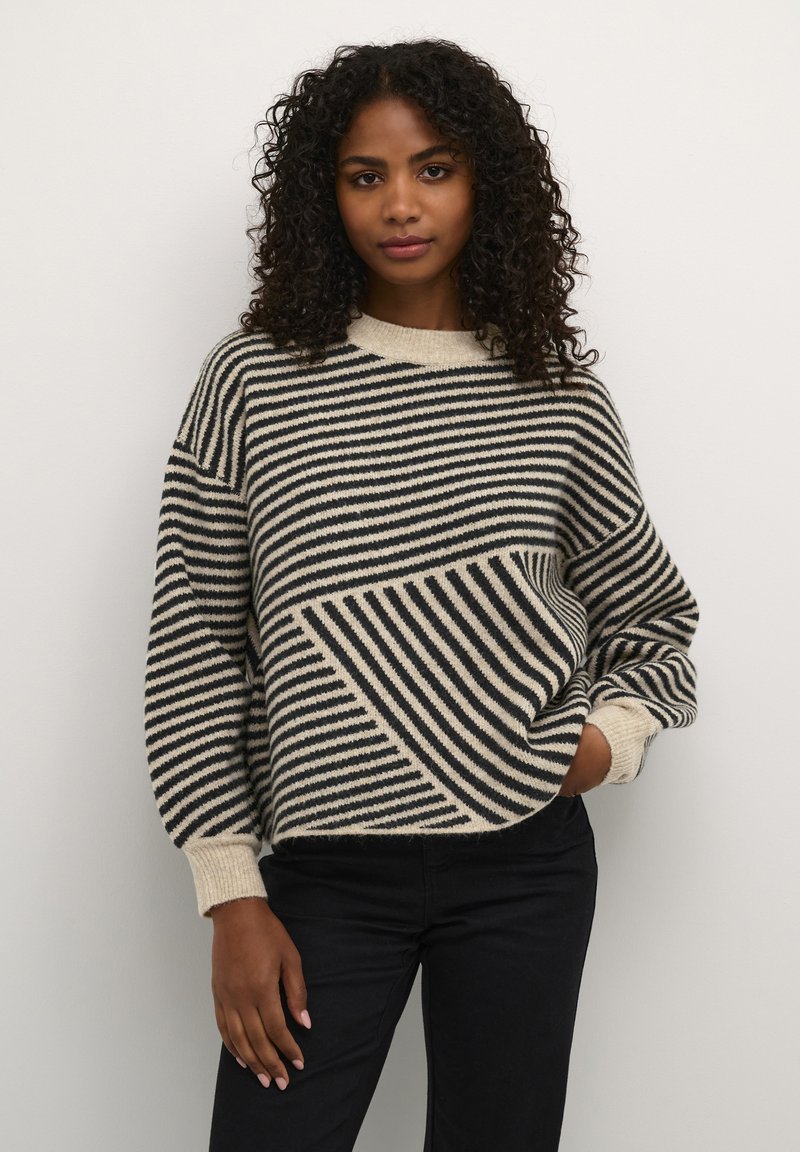 Pull surdimensionné avec des rayures horizontales et diagonales beige et noir, col rond, poignets côtelés et tricot doux et texturé.