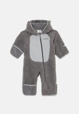Combinaison en polaire grise avec capuche, fermeture éclair et accents contrastants gris clair. Présente une surface douce et texturée ainsi que des poignets élastiques.