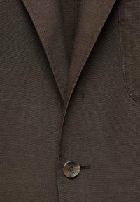 Brązowa marynarka z teksturowanej tkaniny, z wyciętymi klapami, pojedynczym zapięciem na guzik i kieszenią na piersi. Gładkie wykończenie z dopasowanymi krawędziami.