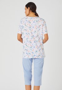 Top de manga corta con estampado floral en blanco y colores pastel, combinado con pantalones cortos de color azul claro. Tela suave, corte relajado.