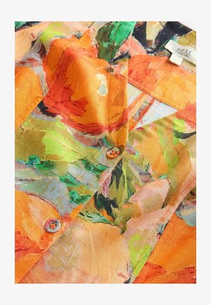 Ziedu krekls ar košiem oranžiem, zaļiem un dzelteniem rakstiem. Izgatavots no viegla auduma, tam ir neliels dekoratīvs pogas akcents.