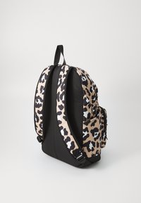 Sac à dos noir et beige avec un motif léopard, côtés rembourrés, bretelles ajustables et une poche latérale avec fermeture éclair.