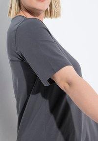 Grijze t-shirt met korte mouwen, gemaakt van zachte katoen. Heeft een ronde halslijn en een losse pasvorm, met zichtbare stiksels langs de mouwen en zijnaad.