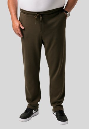 Olivgrüne Jogginghose mit Kordelzugbund, seitlichen Taschen und elastischen Bündchen, kombiniert mit schwarzen Sneakers mit weißen Akzenten.