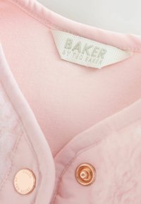 Gaiši rozā audums ar gludu tekstūru, ar uzlīmi, kas apzīmēta ar "BAKER", un zelta tonī snap pogu detaļām. Mīksts un pūkains apkakles uzvalks.