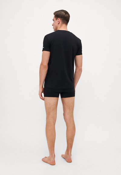 Schwarzes Baumwoll-T-Shirt mit kurzen Ärmeln und rundem Halsausschnitt, kombiniert mit passenden schwarzen Boxershorts. Glatte Textur, lässige Passform.