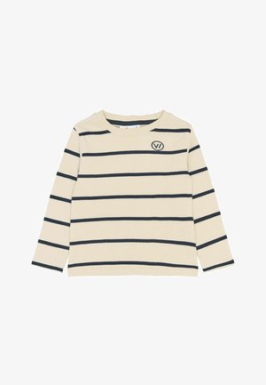 Krém színű, hosszú ujjú ing fekete vízszintes csíkokkal, a bal felső mellrészén egy kis "VI" logóval.