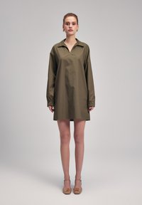Robe chemise olive, à manches longues, avec un col et des poignets élastiques, fabriquée en tissu léger. Design minimaliste, longueur genou.