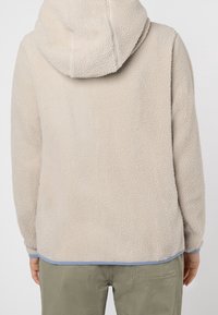 Beige fleece hoodie met een gestructureerd oppervlak, capuchon en lichtblauwe accenten aan de zoom en manchetten. Gezien vanaf de achterkant.