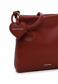 Red leather handbag with a textured finish, featuring a detachable heart-shaped tag embossed with "EMILY&NOAH," and a single shoulder strap.