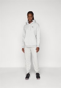 Gray hoodie and sweatpants made of soft material, featuring a front pocket and logo accents; paired with black athletic shoes.