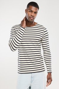 Langärmliges, gestreiftes Hemd in Creme und Marineblau, mit weitem Ausschnitt und taillierten Ärmeln, kombiniert mit hellblauen Jeans.