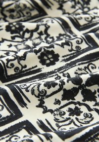 Mustavalkoinen kuviollinen kangas, jossa on kukka- ja geometrisia kuvioita vaaleassa taustassa; sileä rakenne, jossa on elegantteja, kontrastisia motiiveja.