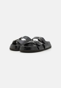 Sorte sandaler i krokodillemønster med to justerbare spenner, rund tå og teksturert såle for bedre grep.