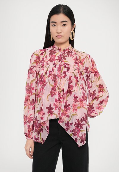 Blouse fleurie avec un motif rose agrémenté d'accents rouge foncé et vert, col rond, fermeture par boutons, et manches larges et fluides.