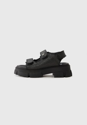 Schwarze Sandalen mit einem strukturierten Mesh-Obermaterial, ausgestattet mit zwei verstellbaren Riemen und einer klobigen, robusten Sohle für besseren Halt und Stabilität.