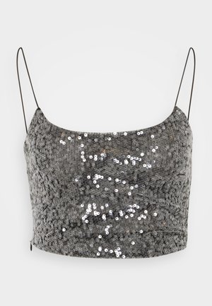 Top corto in paillettes argento con spalline sottili, caratterizzato da una superficie texturizzata e un design aderente. Chiusura con zip a scomparsa sul retro.