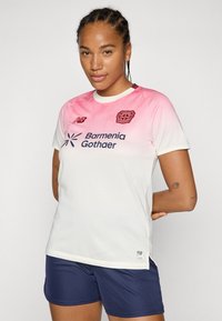 White soccer jersey with a pink gradient at the top. Features a round neck, short sleeves, and printed sponsorship logos. Worn with navy shorts.