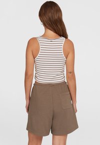 Gestreifter gerippter Tanktop in Weiß und Braun, kombiniert mit braunen Shorts mit einer Gesäßtasche und elastischem Bund. Lässige Passform.