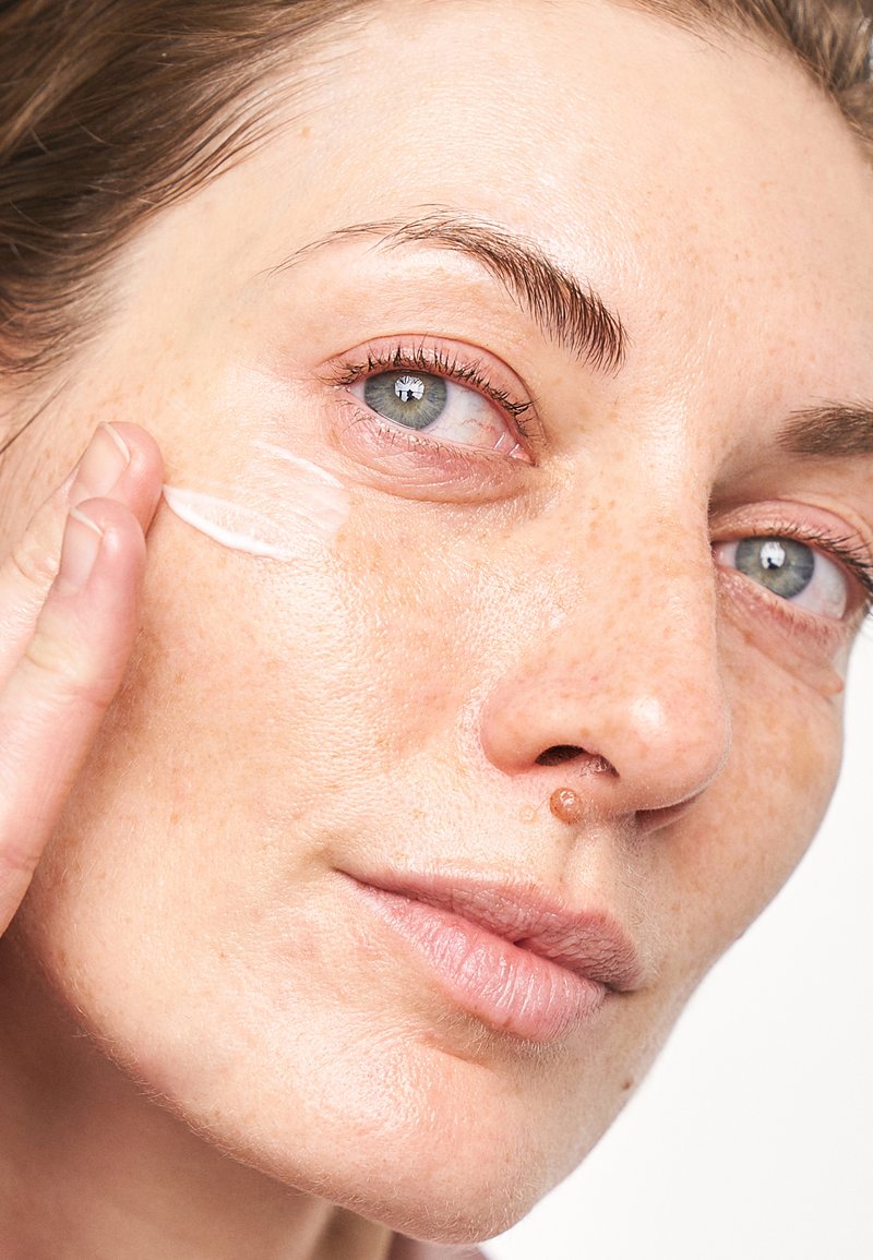 Une crème hydratante appliquée sur une peau claire. Le produit est blanc, lisse et crémeux, améliorant la texture naturelle et l'hydratation.