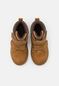 Braune Wildleder-Ankle-Boots mit zwei Klettverschlüssen, runder Zehenpartie und weichem Innenfutter. Bietet ein kontrastierendes braunes Innenleben und eine Gummisohle.