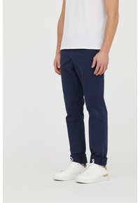 Chinos en coton bleu marine avec une coupe slim, ornés de poignets roulés. Associés à des baskets blanches avec des détails dorés.