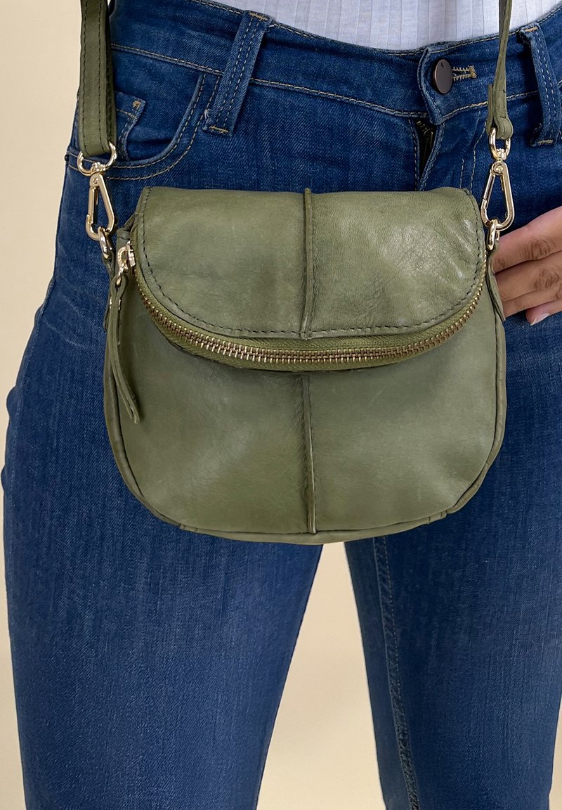 Borsa a tracolla in pelle verde oliva con forma arrotondata, tasca frontale con zip e hardware in tonalità oro. Dotata di tracolla rimovibile.