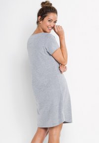Abito t-shirt grigio con maniche corte, caratterizzato da una vestibilità rilassata e una texture morbida, che arriva a metà coscia con scollatura arrotondata.
